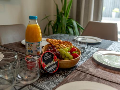 a table with a bowl of fruit and a bottle of orange juice at Pass the Keys Charming Modern Retreat with Private Garden in Hinstock