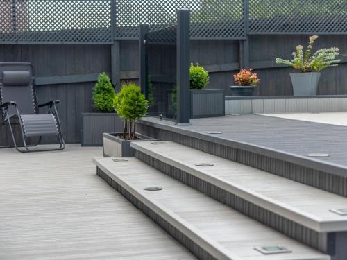 a patio with benches and potted plants at Pass the Keys Charming Modern Retreat with Private Garden in Hinstock
