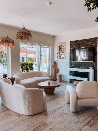 a living room with white furniture and a fireplace at Captain Cook AHOY in Praia da Areia Branca