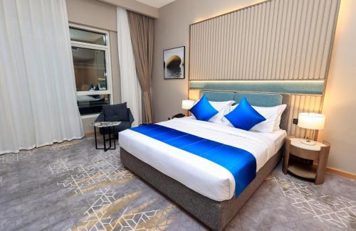 a hotel room with a large bed with blue pillows at Best Western Premier M Four Hotel in Dubai