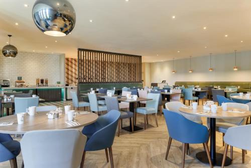 a dining room with tables and chairs at Holiday Inn South Normanton M1, Jct.28 by IHG in South Normanton