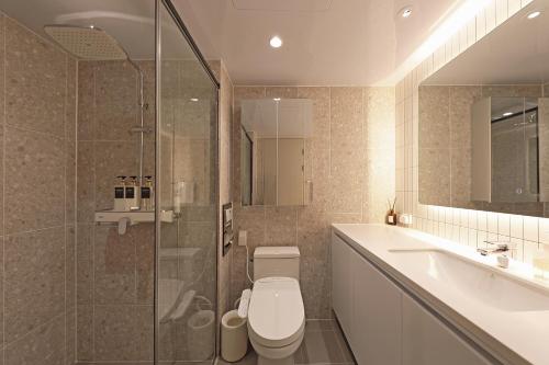 a bathroom with a toilet and a sink and a shower at Elmomento Songdo in Busan