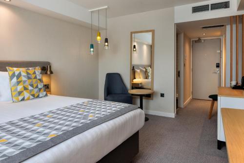 a hotel room with a bed and a chair at Holiday Inn South Normanton M1, Jct.28 by IHG in South Normanton