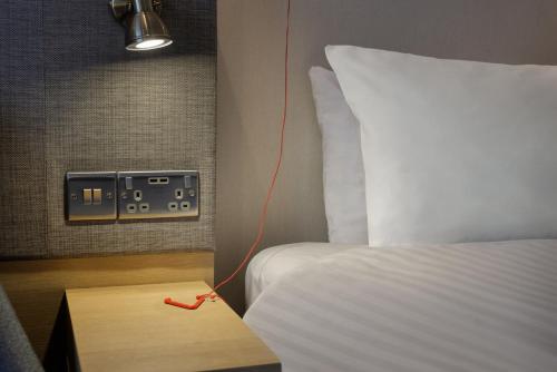 a bedroom with a bed and a light and a table at Holiday Inn South Normanton M1, Jct.28 by IHG in South Normanton