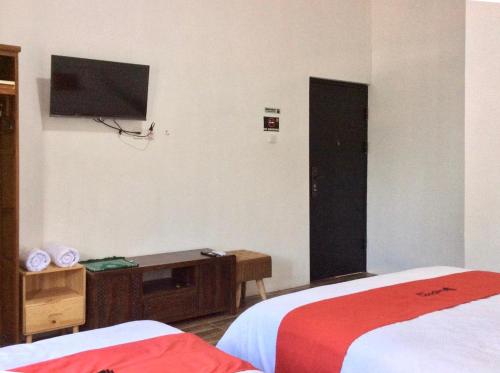 a hotel room with two beds and a flat screen tv at Reddoorz Syariah near Sleman city hall 4 in Sleman
