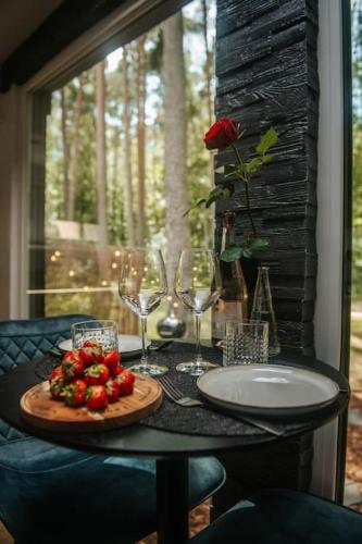 a table with wine glasses and a plate of strawberries at Hot Tub SPA in the Woods in Yarvekyulya