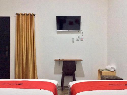 a room with two beds and a desk and a tv at Reddoorz Syariah near Sleman city hall 4 in Sleman