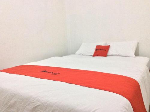 a bed with a red blanket on top of it at Reddoorz Syariah near Sleman city hall 4 in Sleman