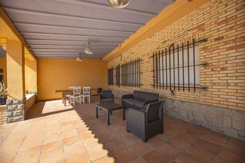a patio with chairs and tables and a brick wall at Villa con piscina y barbacoa para 13 personas cerca del metro in Valencia