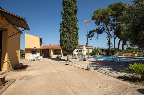 a courtyard with a tree and a swimming pool at Villa con piscina y barbacoa para 13 personas cerca del metro in Valencia