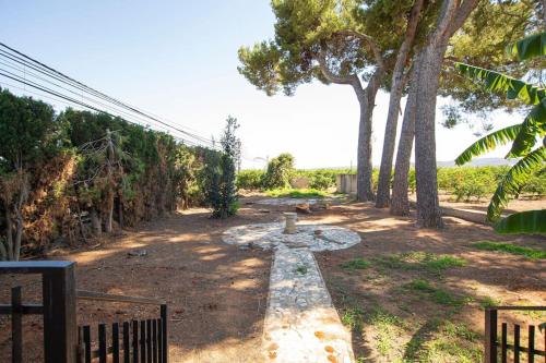 a pathway with a stone bench in a yard with trees at Villa con piscina y barbacoa para 13 personas cerca del metro in Valencia