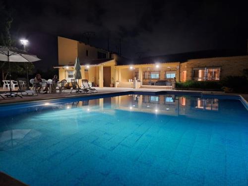 a large swimming pool in front of a house at night at Villa con piscina y barbacoa para 13 personas cerca del metro in Valencia