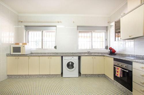a white kitchen with a washing machine in it at Villa con piscina y barbacoa para 13 personas cerca del metro in Valencia