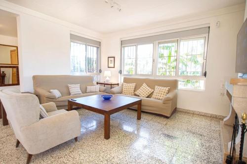 a living room with a couch and a table at Villa con piscina y barbacoa para 13 personas cerca del metro in Valencia