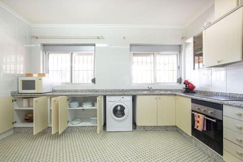 a large kitchen with a washer and dryer in it at Villa con piscina y barbacoa para 13 personas cerca del metro in Valencia