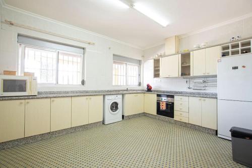 a large kitchen with white cabinets and a washer and dryer at Villa con piscina y barbacoa para 13 personas cerca del metro in Valencia