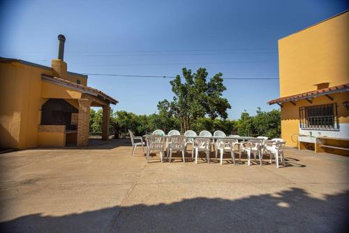 a group of white chairs and a table in front of a building at Villa con piscina y barbacoa para 13 personas cerca del metro in Valencia