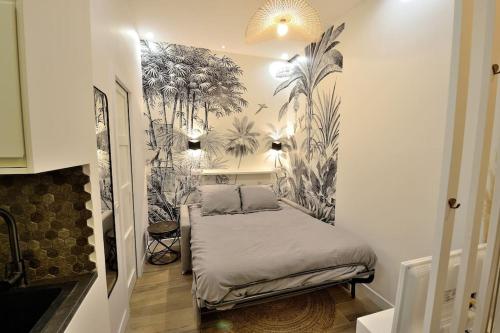 - une chambre avec un lit orné d'une fresque murale de palmiers dans l'établissement Tiny cosy studio NAMASTAY in trendy Canal St Martin area, à Paris