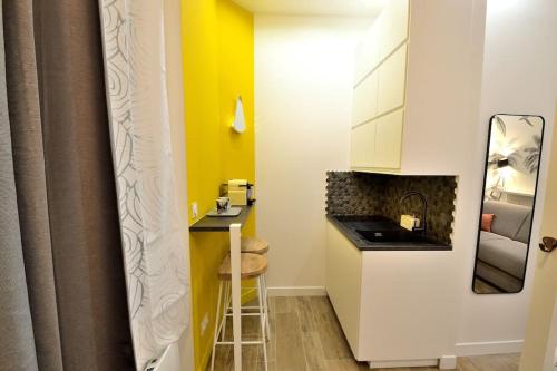 une petite cuisine avec un mur d'accent jaune dans l'établissement Tiny cosy studio NAMASTAY in trendy Canal St Martin area, à Paris