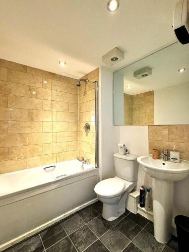 a bathroom with a tub and a toilet and a sink at 2 Bed ensuite with Balcony and Free onsite Secure Parking in Manchester