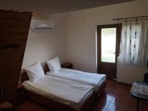 una camera da letto con un letto con lenzuola bianche e una finestra di Aterman's Cottages a Perşani