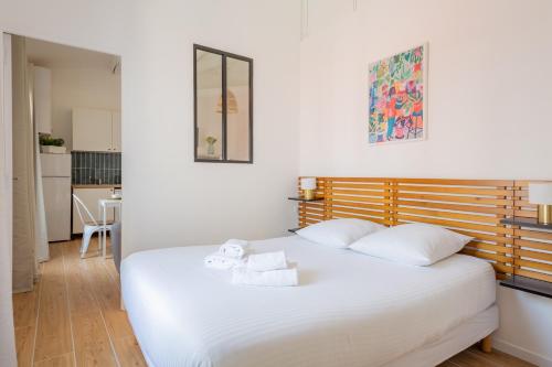 Cet appartement comprend une chambre avec un lit blanc et une cuisine. dans l'établissement La Corderie - Sous les toits de Marseille, à Marseille