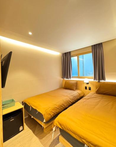 a hotel room with two beds and a flat screen tv at Well Plus Guest House in Seoul