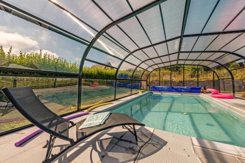 - une piscine avec un toit en verre et une chaise à côté dans l'établissement Ti Braz Magnifique Maison Piscine, à Plouguerneau