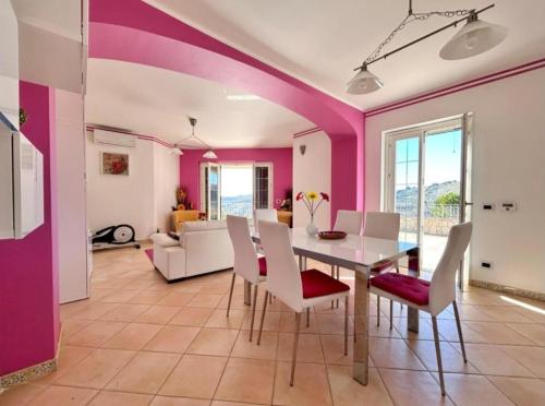a dining room with pink walls and a table and chairs at ENNA Villa del Sole e delle Stelle in Enna