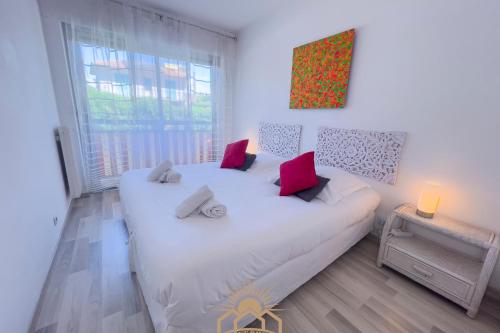une chambre avec un grand lit blanc avec des oreillers roses dans l'établissement LE SURCOUF Appartement by 4 By SUNSET, au Cannet
