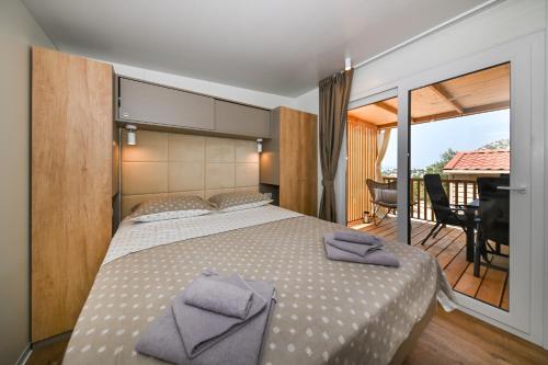 a bedroom with a large bed and a balcony at Kamp Oaza Lučica in Drage