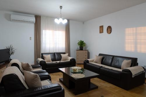 a living room with black leather couches and a table at Green Art House in Kovilovo
