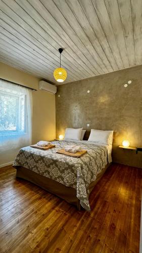 a bedroom with a large bed with a wooden floor at Villa Vista in Asprogerakata