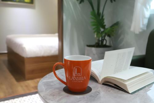 an orange coffee mug sitting on a table with a book at Lanura Apartments and Hotel in Ho Chi Minh City