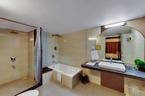 a bathroom with a tub and a sink and a mirror at Quality Inn Regency, Nashik in Nashik