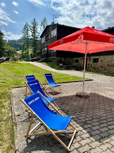 two chairs and a red umbrella and an umbrella at Chata Brian in Horní Bečva
