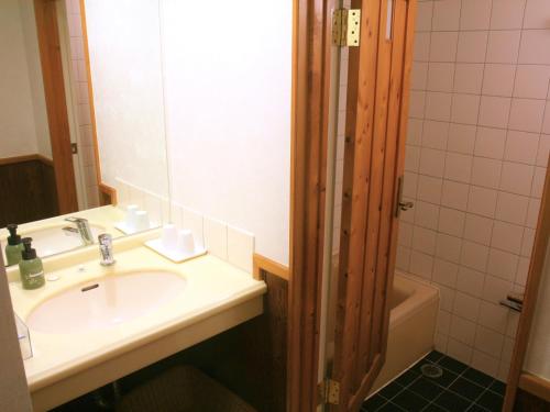 a bathroom with a sink and a mirror and a tub at Hotel Sanrakuso in Shirahama