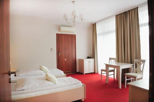 a hotel room with two beds and a table at Malutkie Resort in Radomsko