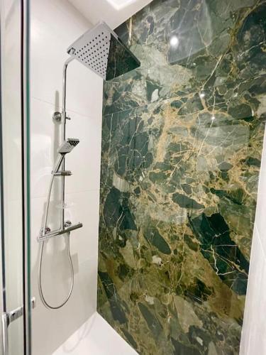 La salle de bains est pourvue d'une douche et d'un mur en pierre. dans l'établissement Clim Ascenseur R4 T2 moderne au cœur de Toulouse, à Toulouse