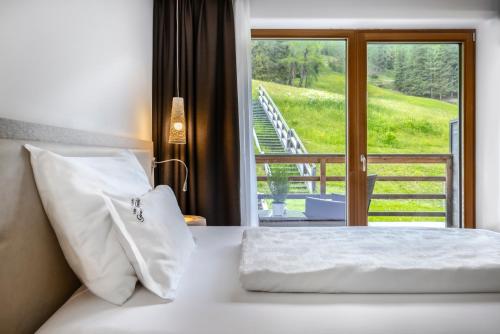 a bedroom with a bed with a view of a balcony at Alpine Hotel Gran Foda' in San Vigilio Di Marebbe