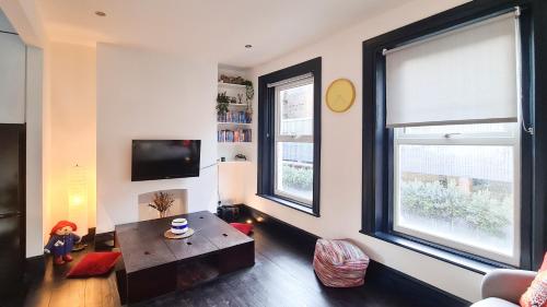 a living room with a table and two windows at Unique and cozy apartment in central London in London