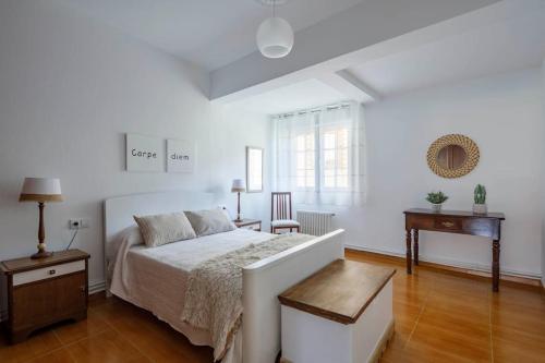 a white bedroom with a bed and a desk at Casa Pilara in Lousame