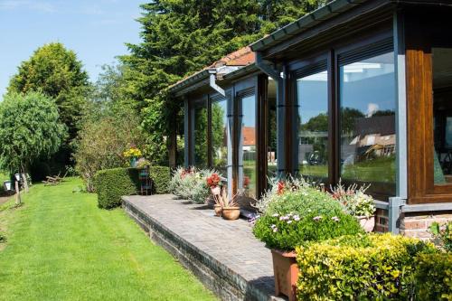 a house with large windows and plants in a yard at Vakantiehuis De Stokerij in Oudenburg