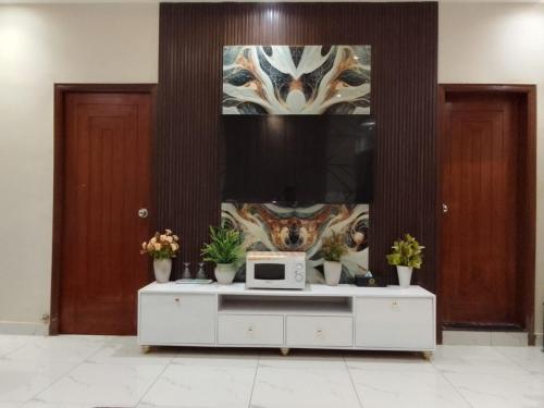 a living room with a tv and a white cabinet at Diplomat Fort Boutique Hotel in Karachi