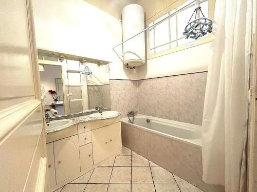 une salle de bain avec une baignoire, un lavabo et un miroir dans l'établissement Sublime Loft dans un Ancien Palace 2 pas de la Mer, à Menton