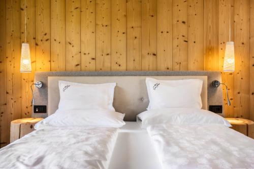 two beds in a room with wooden walls at Alpine Hotel Gran Foda' in San Vigilio Di Marebbe