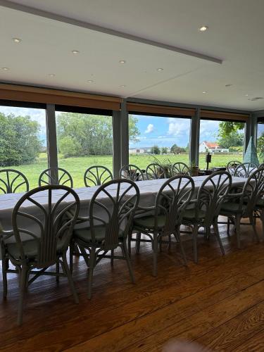a long table and chairs in a room with windows at Vakantiehuis De Stokerij in Oudenburg