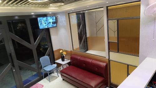 a waiting room with a red couch and a tv at Hotel Fab International in Kolkata