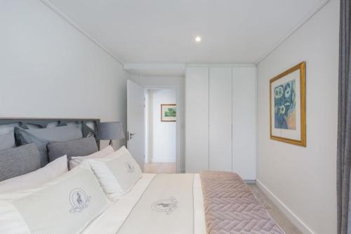 Central Southern Suburbs Leafy Village Neighbourhood في كيب تاون: غرفة نوم بيضاء مع سرير وأريكة