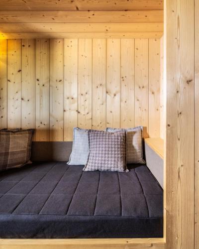 a bed in a wooden room with wooden walls at Alpine Hotel Gran Foda' in San Vigilio Di Marebbe